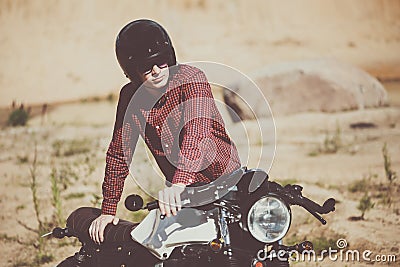 Biker with helmet start a vintage custom motorcycle. Outdoor lifestyle toned portrait Stock Photo