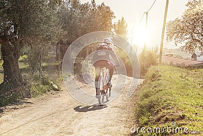 Biker person on a bicycle practicing sports in the nature against a sun flare. Lifestyle and active concept with empty copy space. Stock Photo