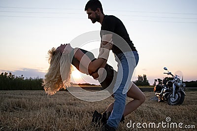 Bikers man and woman stopped at the side of the road to rest and kiss passionately. Photos of loving motorcyclists at sunset. The Stock Photo