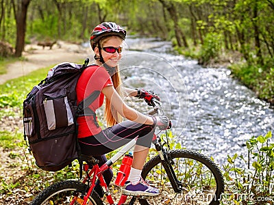 Bikes cycling girl with big rucksack cycling fording throught water into park. Stock Photo