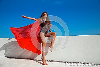 Bikini model with long hair. Beautiful girl with red scarf on the beach over blue sky. Fashion sexy brunette model woman with Stock Photo