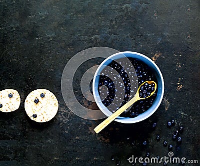 Bilberry in blue bowl on vintage rusty metal background. Concept of organic berries. Stock Photo