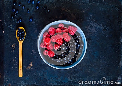 Bilberry and raspberries in blue bowl, the concept of organic berries bowl on vintage rusty metal background. Stock Photo