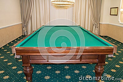 Billiard table with green baize stands in a luxurious living room, a concept of sports and Hobbies for the wealthy Stock Photo