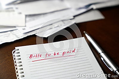 Bills to be paid, red color written words on notebook with bills and invoices at the background Stock Photo