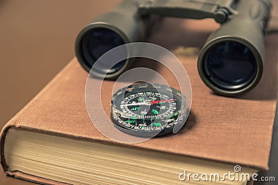 Binoculars, compass and book. Stock Photo