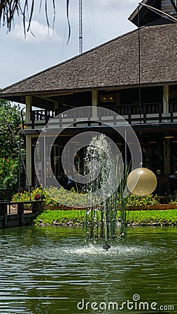 Bintaro, March 2022 - Green water pond with fountain and wooden traditional gazebo outdoor design of Telaga Sampireun Restaurant Editorial Stock Photo