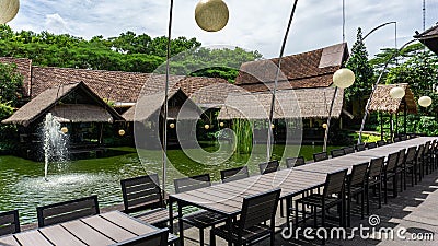 Bintaro, March 2022 - Outdoor natural dining wooden table with round lamp and water fountain of Telaga Sampireun Restaurant Editorial Stock Photo