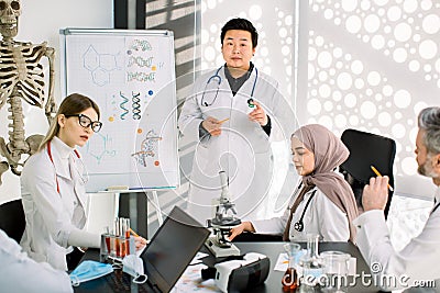 Biochemistry, pharmacology, drug industry, clinical trials. Young Asian doctor talks about the results of clinical trial Stock Photo