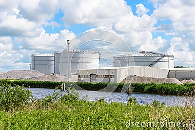 Biogas plant with large biomass digesters along a canal Stock Photo