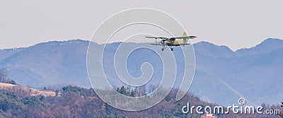 Biplane flying over mountainous region Editorial Stock Photo