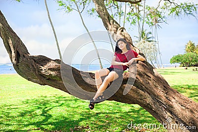 Teen girl in tree at Kawaikui Beach park, Oahu, Hawaii Stock Photo