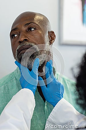 Biracial female doctor wearing medical gloves examinating african american male patient Stock Photo