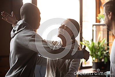 Biracial girl hugging african guy friends gathered in cafeteria Stock Photo