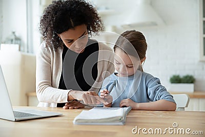 Biracial mom help Caucasian daughter with online lesson Stock Photo