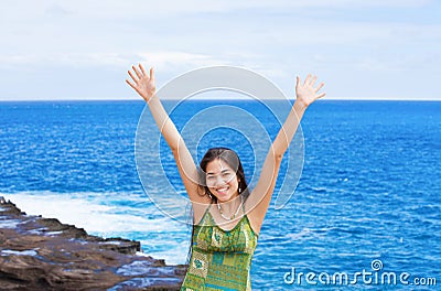 Biracial teen girl arms raised by ocean water in praise Stock Photo