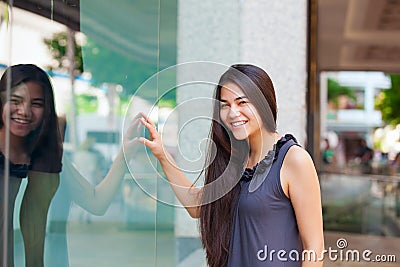 Biracial teen girl window shopping in urban setting downtown Stock Photo