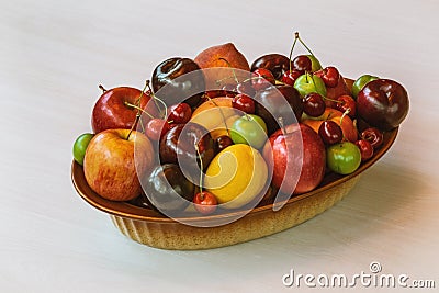 Bird eye view of a bowl of colorful mixed fruit, apples, peaches, green and red plums, cherries and lemon. Stock Photo