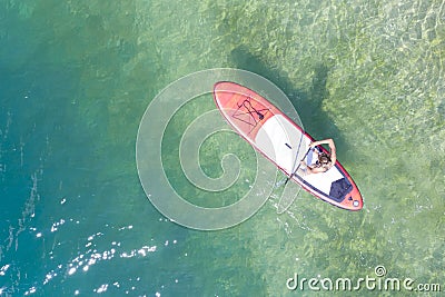 Bird`s eye view to girl on SUP surf board on turquoise clean lake water Stock Photo