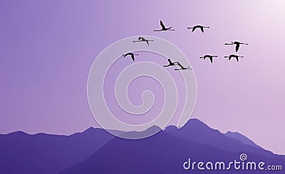 Birds flying against purple landscape in the background Stock Photo