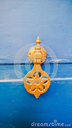 Bright yellow brass knocker on a vibrant blue door, Morocco Stock Photo