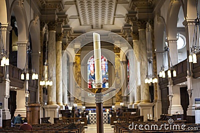 BIRMINGHAM, UK - March 2018 One Used White Candle Standing in the Middle Foregroound. St. Philips Cathedral Interior Editorial Stock Photo