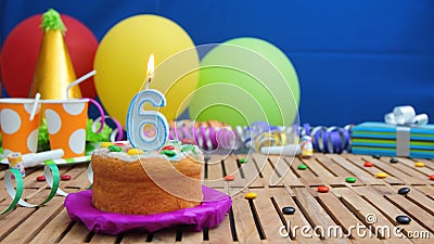 Birthday 6 cake with candles on rustic wooden table with background of colorful balloons, gifts, plastic cups and candies Stock Photo