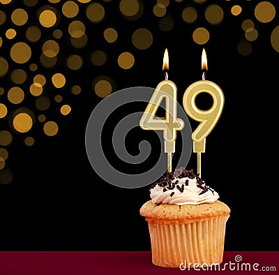 Birthday candle with cupcake - Number 49 on black background with out of focus lights Stock Photo