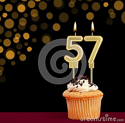 Birthday candle with cupcake - Number 57 on black background with out of focus lights Stock Photo