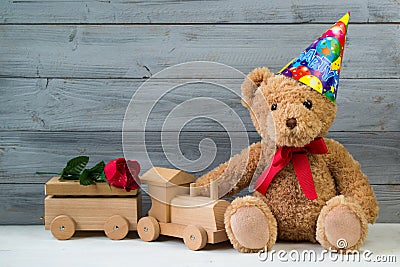 Birthday concept, teddy bear in party cap and wooden toy train Stock Photo