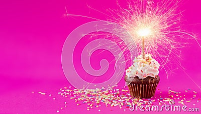 Birthday Cupcake with a sparkler at pink background Stock Photo