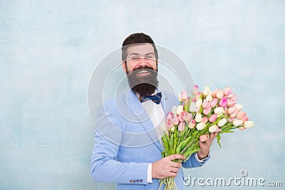 Birthday greetings. Best flowers for girlfriend. Flowers for her. Man bearded suit bow tie hold tulips bouquet Stock Photo