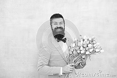 Birthday greetings. Best flowers for girlfriend. Flowers for her. Man bearded suit bow tie hold tulips bouquet Stock Photo