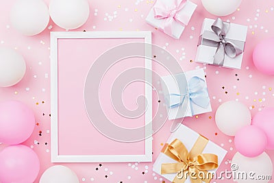 Birthday or holiday mockup with frame, gift box, pastel balloons and confetti on pink table top view. Flat lay composition. Stock Photo