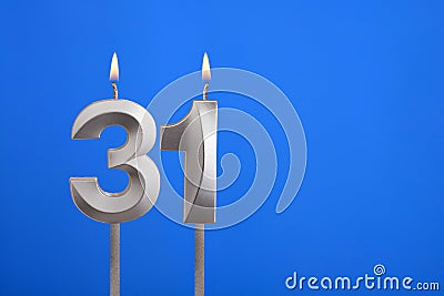 Birthday number 31 - Candle lit on blue background Stock Photo