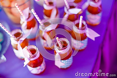 Birthday party concept, candy bar for children. A lot of bottles of apple juice, special labels on it, white and pink straws on Stock Photo