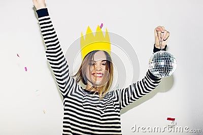 Birthday party, new year carnival. Young smiling woman on white background celebrating brightful event, wears stripped Stock Photo