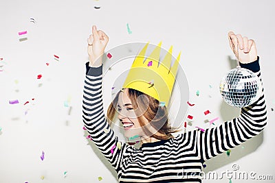 Birthday party, new year carnival. Young smiling woman on white background celebrating brightful event, wears stripped Stock Photo