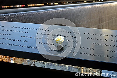 Birthday white rose near name of the victim engraved on bronze parapet of 9/11 Memorial at World Trade Center - New York, USA Editorial Stock Photo