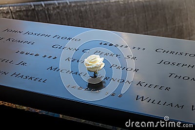 Birthday white rose near name of the victim engraved on bronze parapet of 9/11 Memorial at World Trade Center - New York, USA Editorial Stock Photo