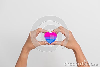 Bisexuality Celebrate Day and LGBT pride month, LGBTQ+ or LGBTQIA+ concept. Hand holding purple, pink and blue heart shape for Stock Photo