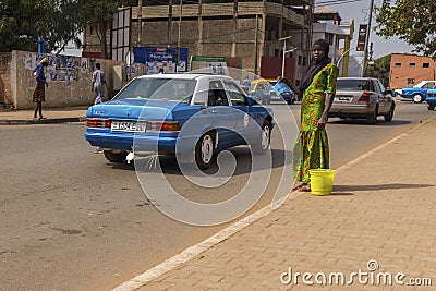 Young african girl wearing an hijab selling water in plastic bags near the Bandim market in the city of Bissau Editorial Stock Photo