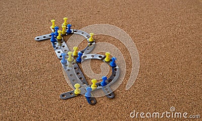 Bitcoin character made of pieces of metal and yellow and blue pins, cork board background. Stock Photo