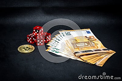 Bitcoin coin, a pile of Euro banknotes and a few red cubes lie side by side on a dark background Stock Photo