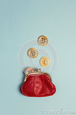 Bitcoin coins falling in red money purse on blue background. Co Stock Photo