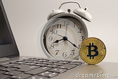 Bitcoin on the computer keyboard and alarm clock Stock Photo