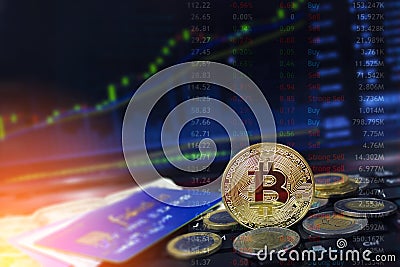 Bitcoin currency with credit cards and coins on laptop keyboard with rising price charts in the background. Stock Photo