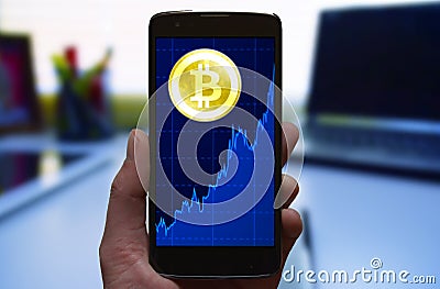 Bitcoin price growth graph. Cryptocurrency Bitcoin symbol and growth chart at the smartphone screen, smartphone in the hand. Stock Photo
