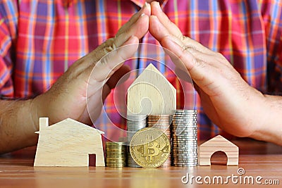 Bitcoin infront of coin stack model home with hand made triangle pattern , protect bitcoin tread concept Stock Photo