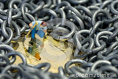 Bitcoin mining by miniature figure holding shovel digging on shiny golden physical Bitcoin Crpto currency coin surround by metal Stock Photo